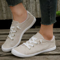 Women's creamy-white low-top fabric sneakers with a rubber sole on a neutral background.