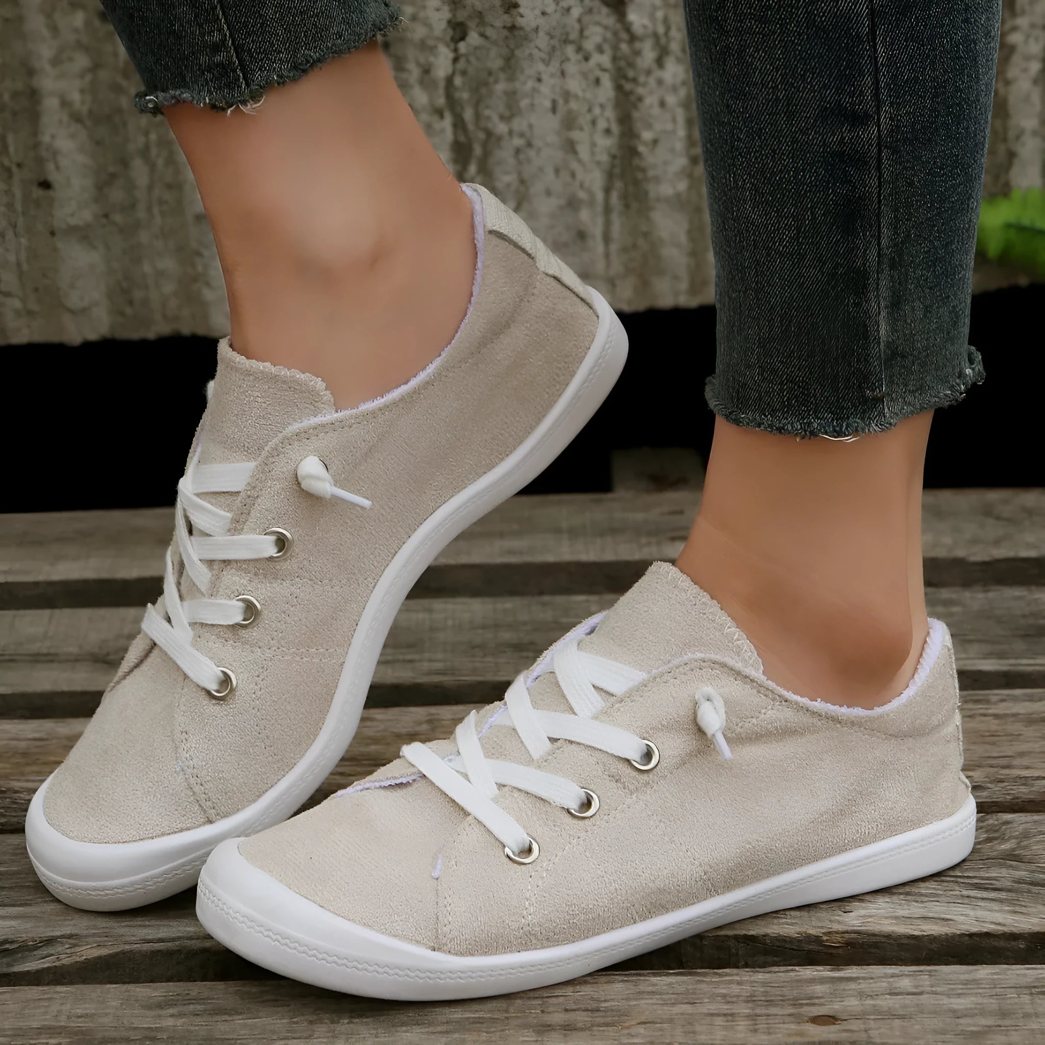Women's creamy-white low-top fabric sneakers with a rubber sole on a neutral background.