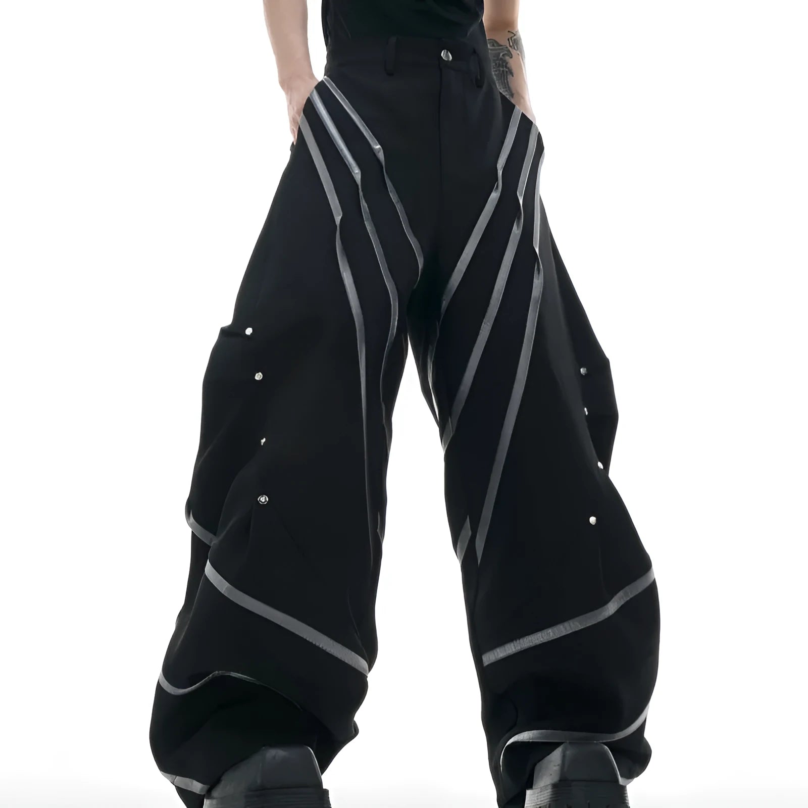 Men's black trousers with three-dimensional cutting, metal striped rivets, and pleated detailing on a hanger.