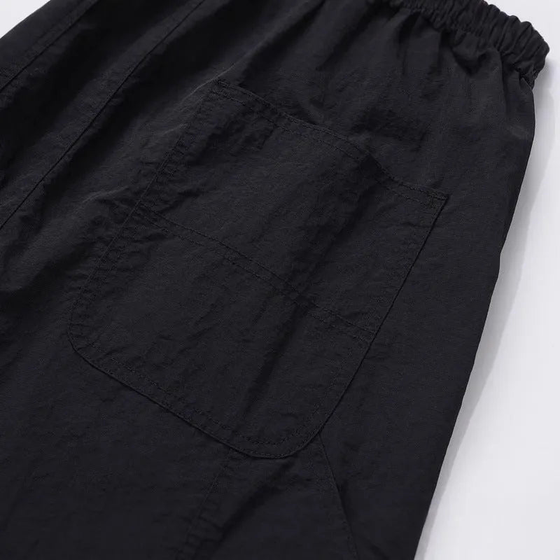 Black men's baggy paratrooper trousers with a drawstring elastic waistband on a plain background.