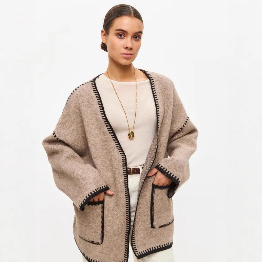 Loose mid-length knitted cardigan sweater coat with a lace-up front, shown in a neutral colour.