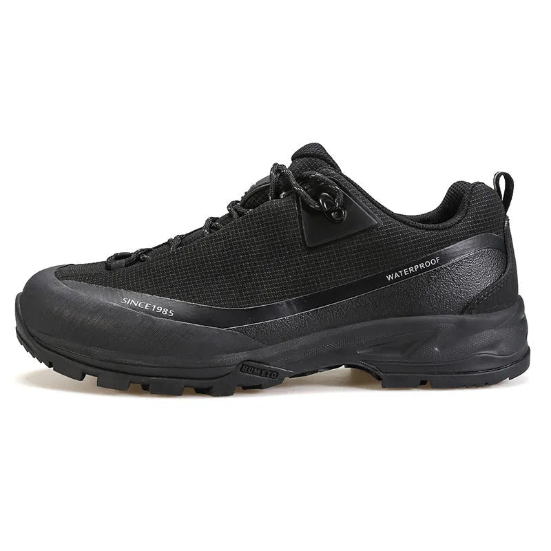 Low-top hiking boots in black with leather mesh upper, rubber outsole, and front lace-up design on a neutral background.