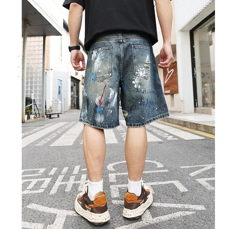 Blue denim shorts for men with ripped knees and graffiti print, featuring a straight leg and a zipper fly