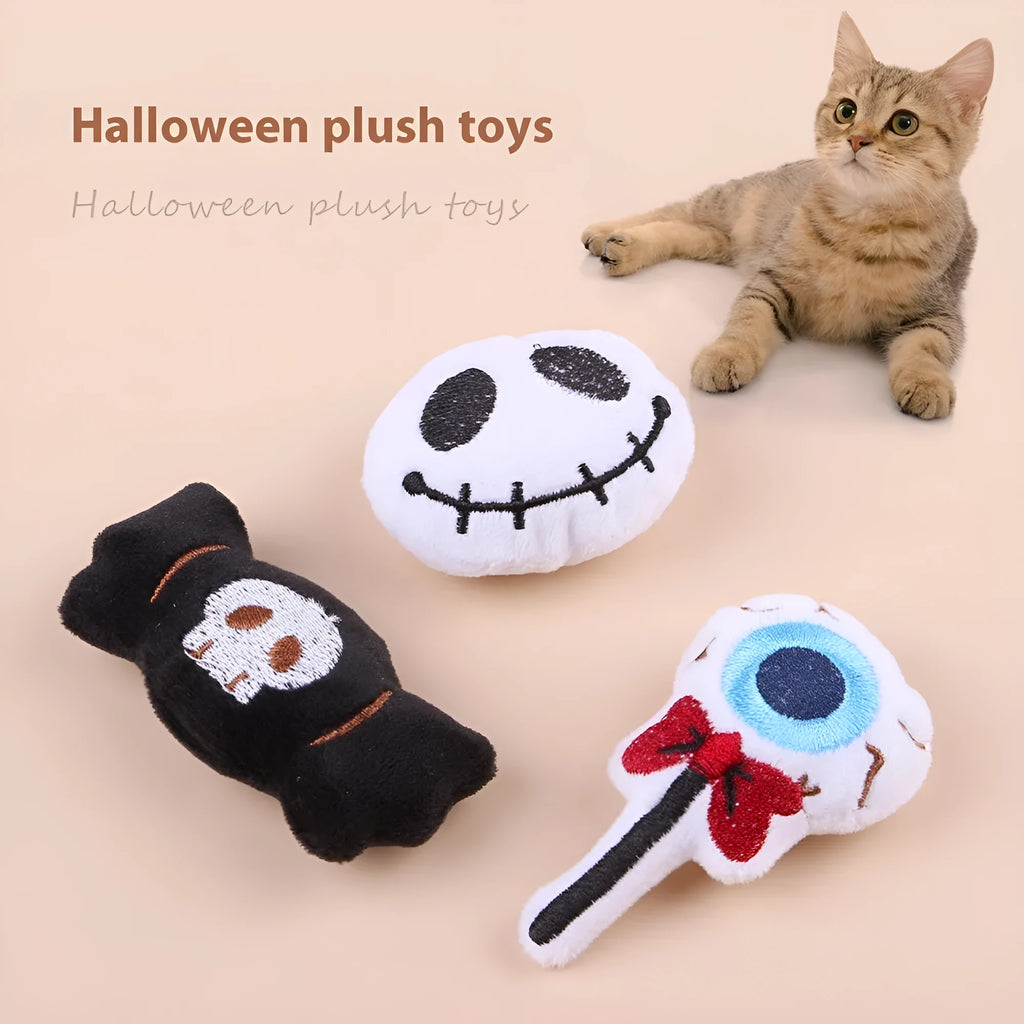 Small plush cat teaser toy in candy, eyes, and skull designs on a blue background.