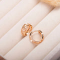 Rose gold hollowed out heart and leaf shaped copper earrings on a white background.