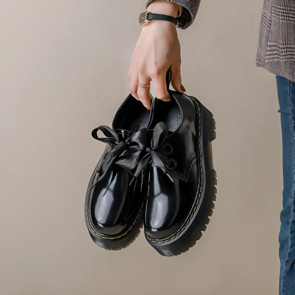 Women's black thick-soled leather shoes with cross-strap closure and ribbon detailing
