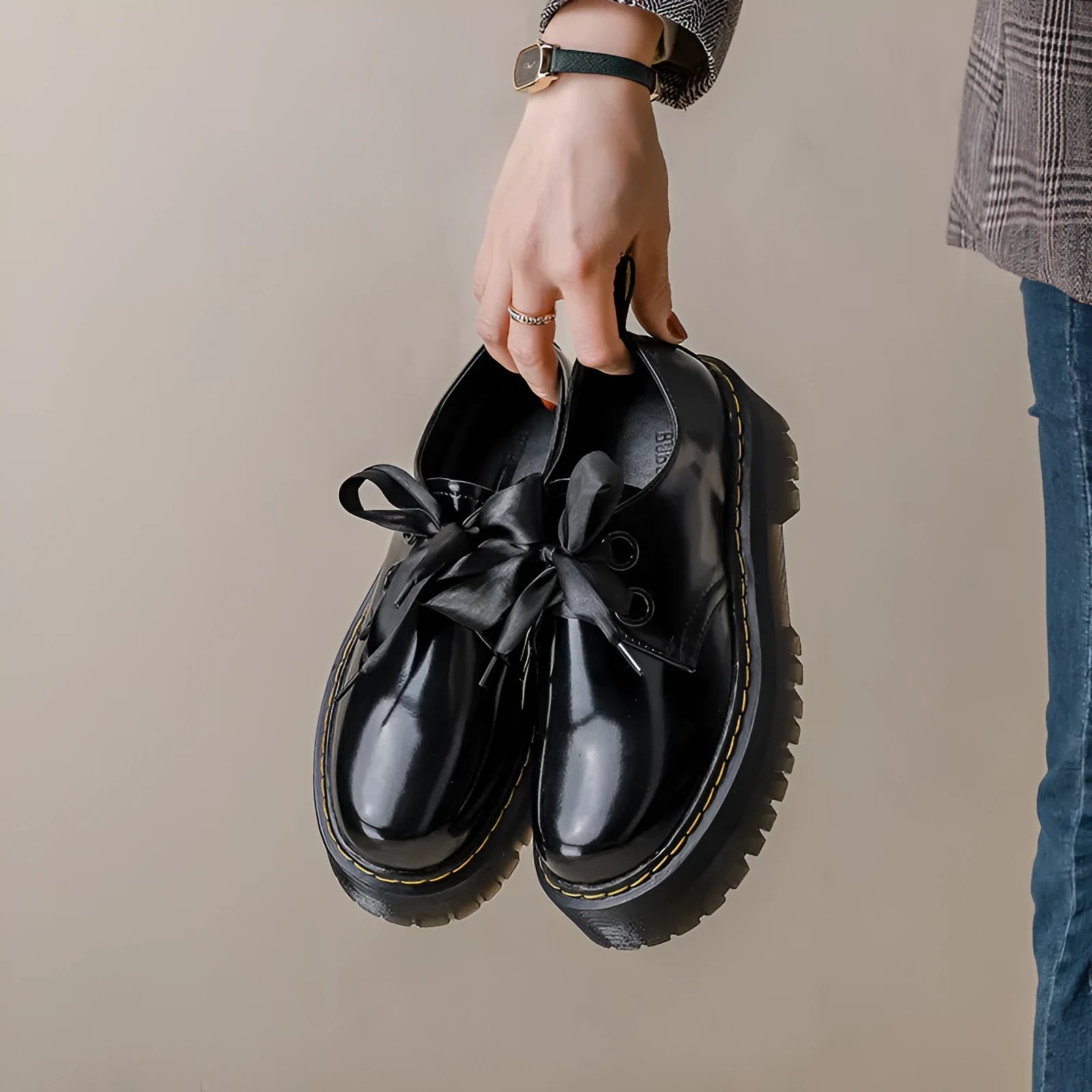 Women's black thick-soled leather shoes with cross-strap closure and ribbon detailing