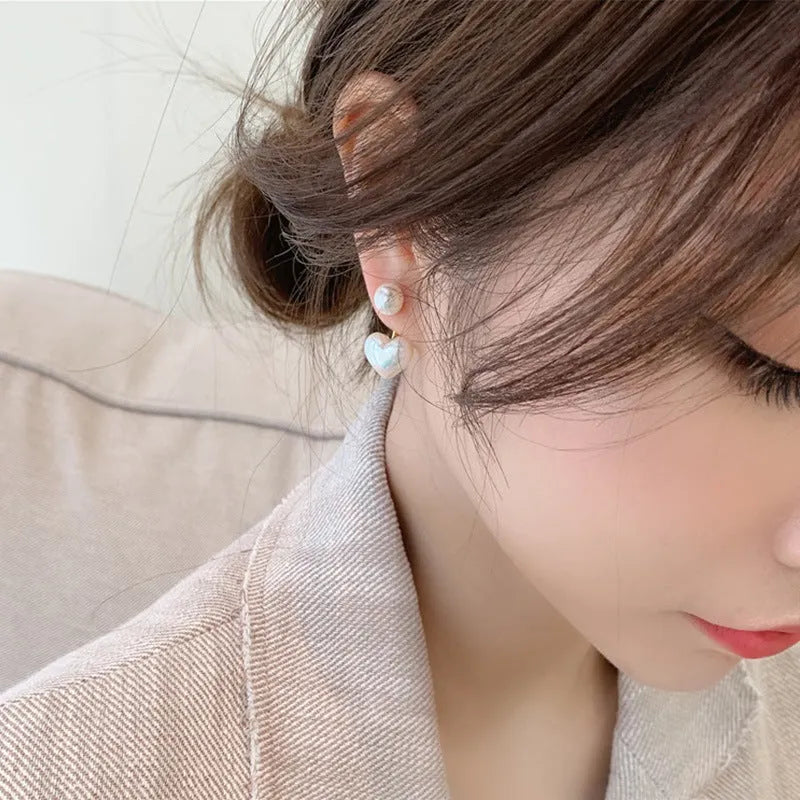 Women's silver-toned heart-shaped stud earrings with central gemstone inlay on a white background.