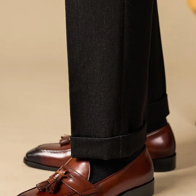Men's black leather tassel loafers with rubber sole shown from side view