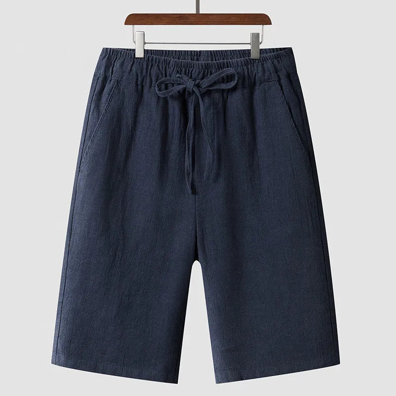 Men's beige linen shorts with a loose cropped fit and mid waistband.