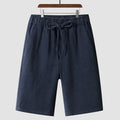Men's beige linen shorts with a loose cropped fit and mid waistband.