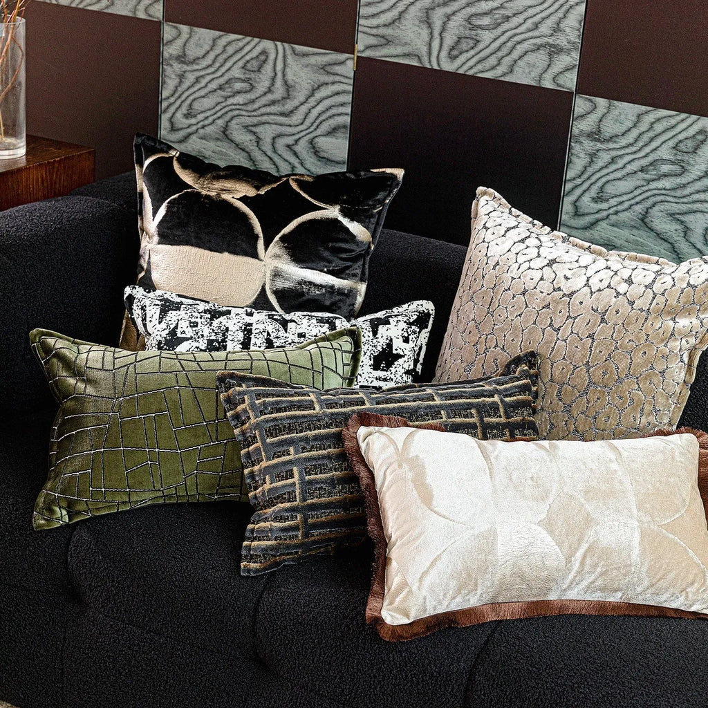 Black and gold abstract pattern decorative flannel pillow with removable cover on a grey sofa.