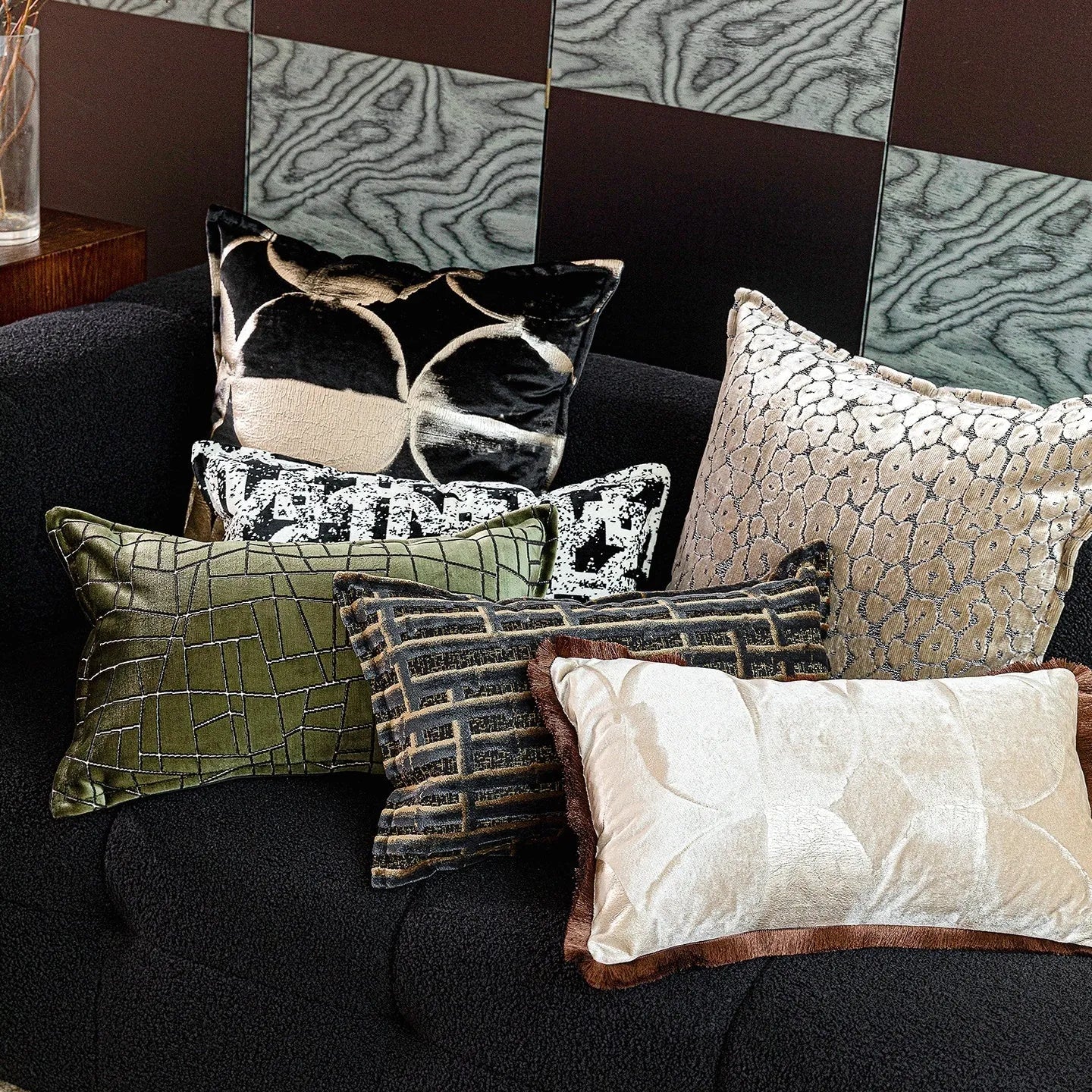 Black and gold abstract pattern decorative flannel pillow with removable cover on a grey sofa.