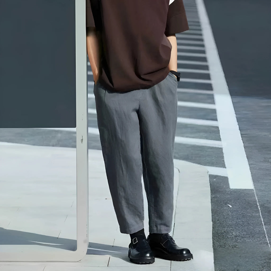 Men's loose straight-leg casual trousers in beige with a drawstring waistband laid flat.
