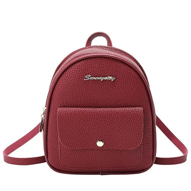 Small black PU leather women's shoulder backpack worn as a backpack, showing zipper closure and compact size.