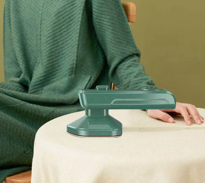 Dark green hand-held steam iron with ceramic panel showing dual temperature buttons and compact design