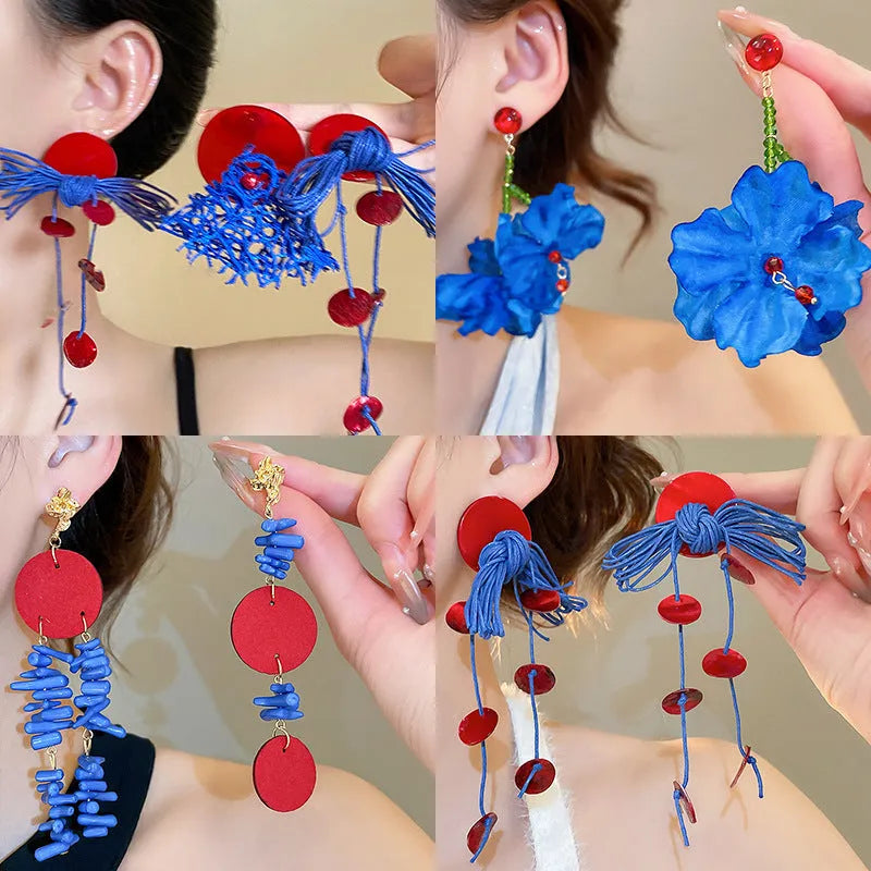 Women's geometric earrings with blue resin flower and silver needle on cloth background