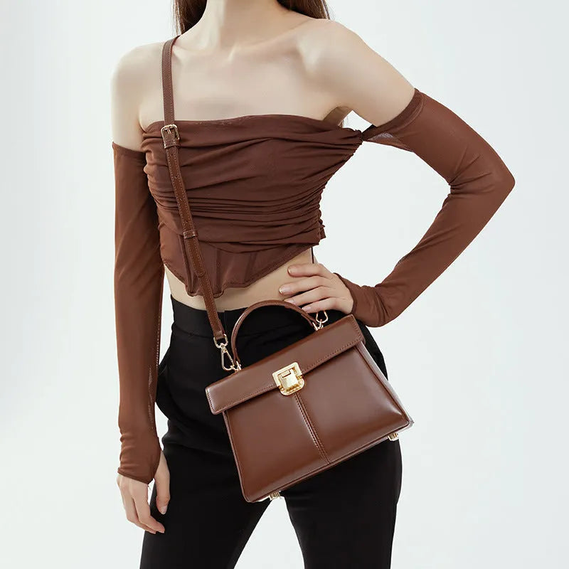 Women's black leather shoulder bag with vachette clasp showing internal zippered pocket