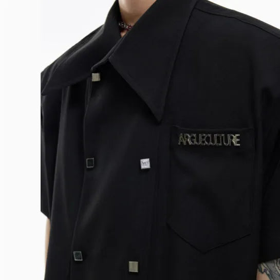 Man wearing a loose fit blue short sleeve casual shirt with a lapel collar and splicing detail.