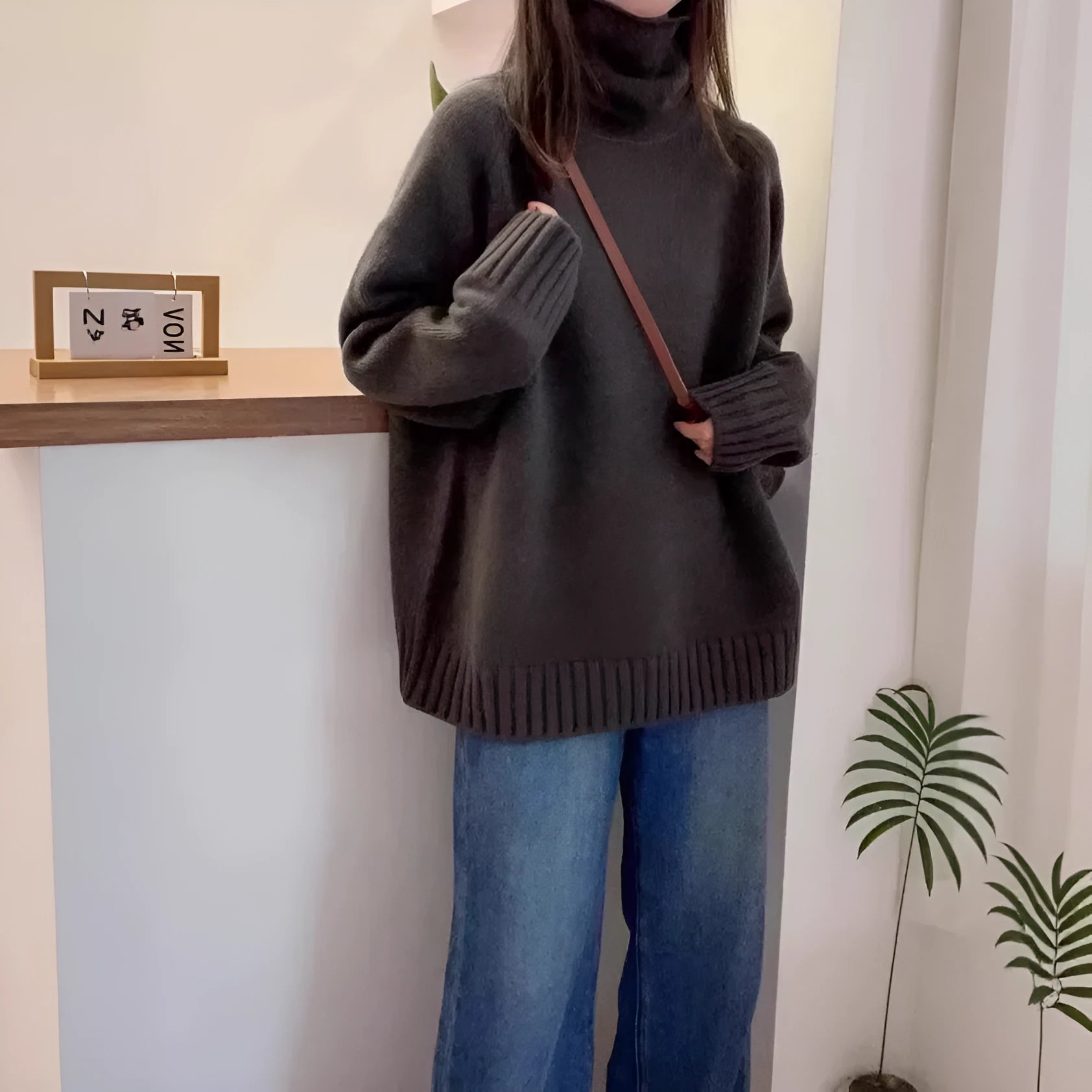A woman's loose-fitting thick turtleneck sweater in a solid colour with a 3D textured pattern.