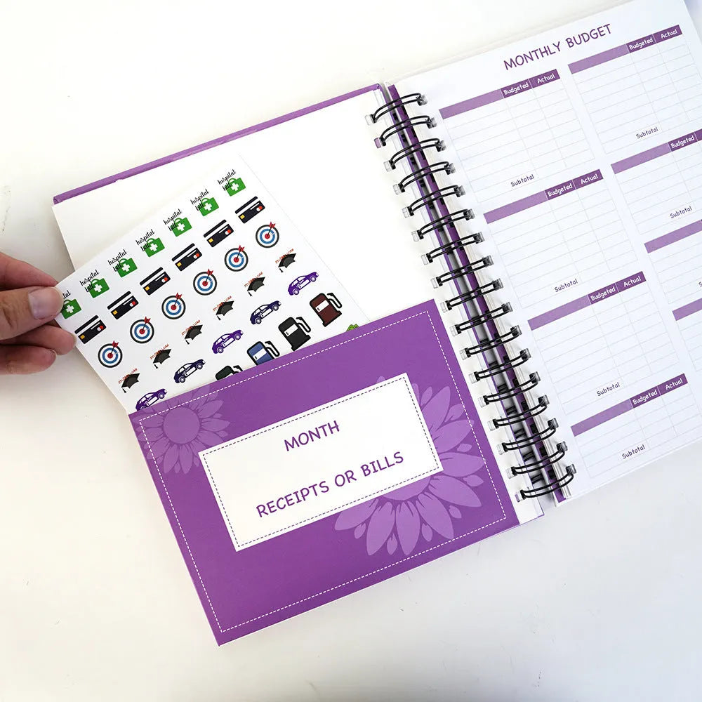 Purple coil-bound budget notebook with stickers for monthly financial planning showing Daolin paper pages
