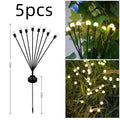 Solar-powered LED firefly ground spike light with multiple heads inserted along a garden path.
