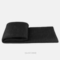 Grey and white plaid bed runner blanket with matching pillowcase and round leather-look pillow on a bed.