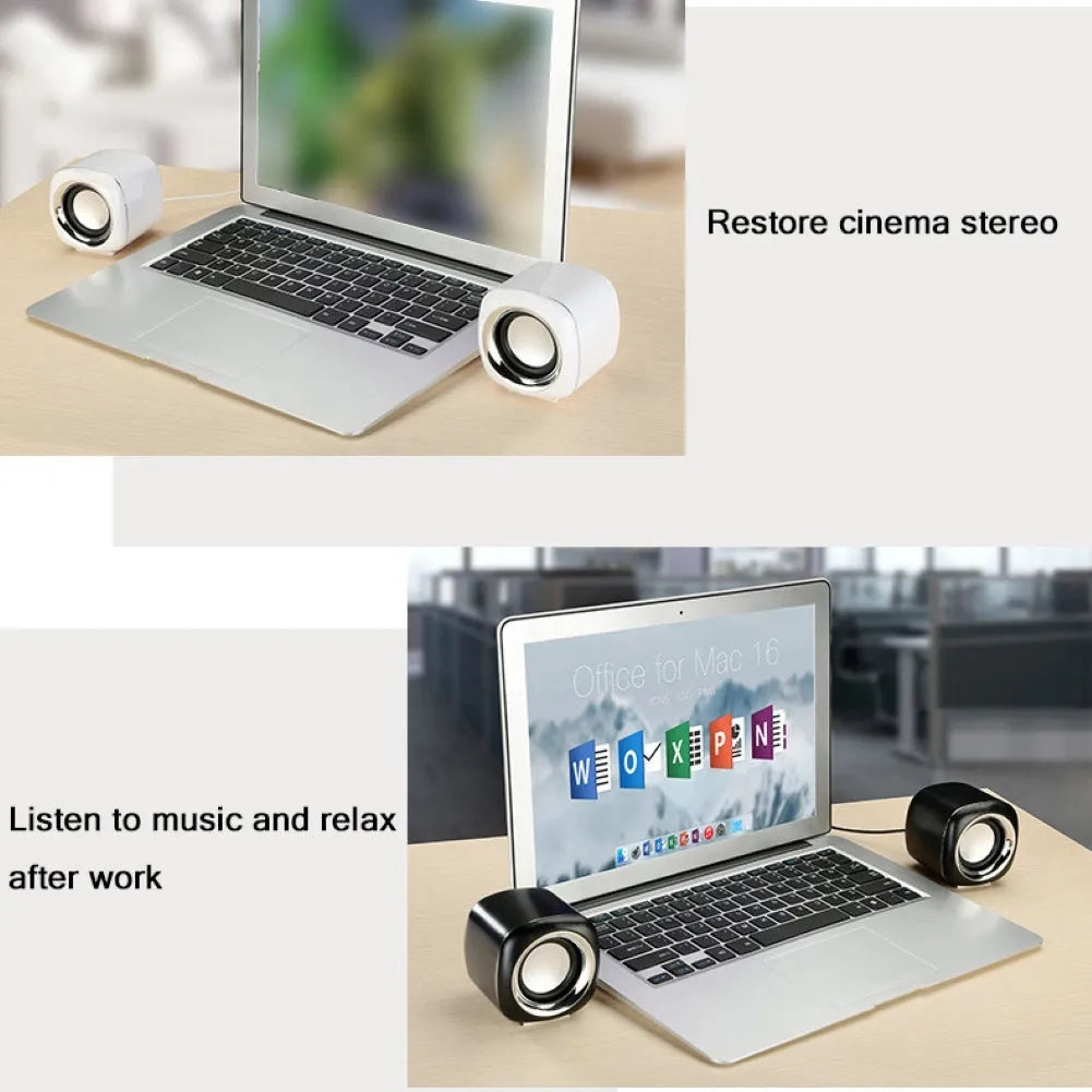 A pair of small black wired computer speakers on a desktop next to a laptop.