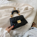 Purple soft PU leather small square shoulder bag with a long strap on a table.