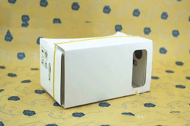 Pink and white foldable cardboard VR glasses headset for smartphones, showing 3D lenses and rubber head strap.
