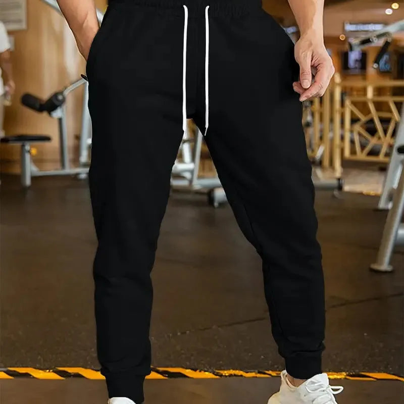 Man wearing loose grey linen-style trousers with an elastic drawstring waist, side view.