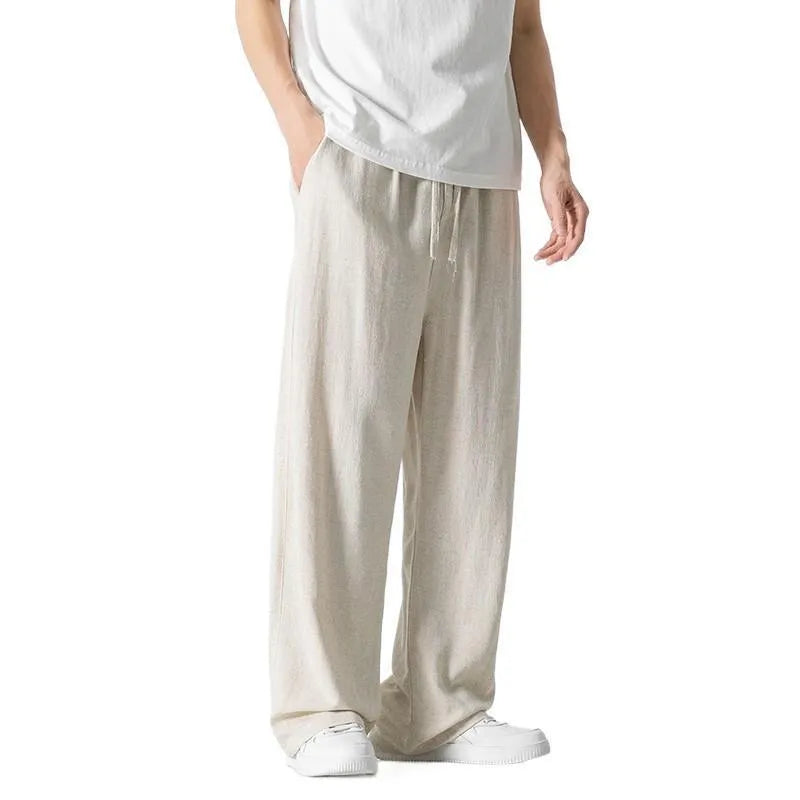 Men's beige linen-style trousers with a loose straight-leg fit and drawstring waist, laid flat.