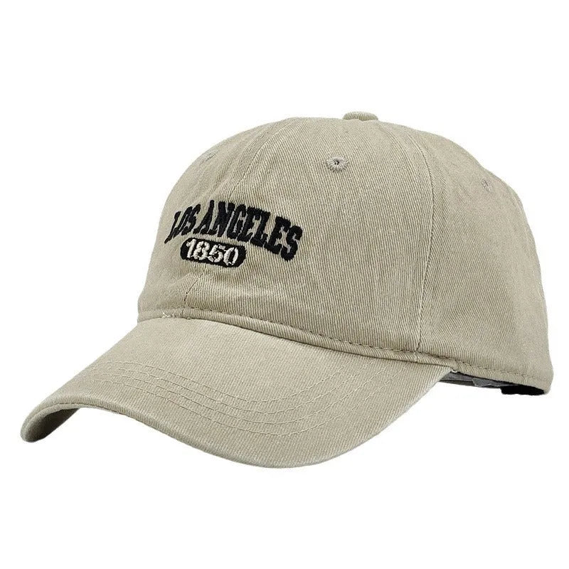 Retro personalised washed distressed embroidered peaked cap in beige colour on a wooden background