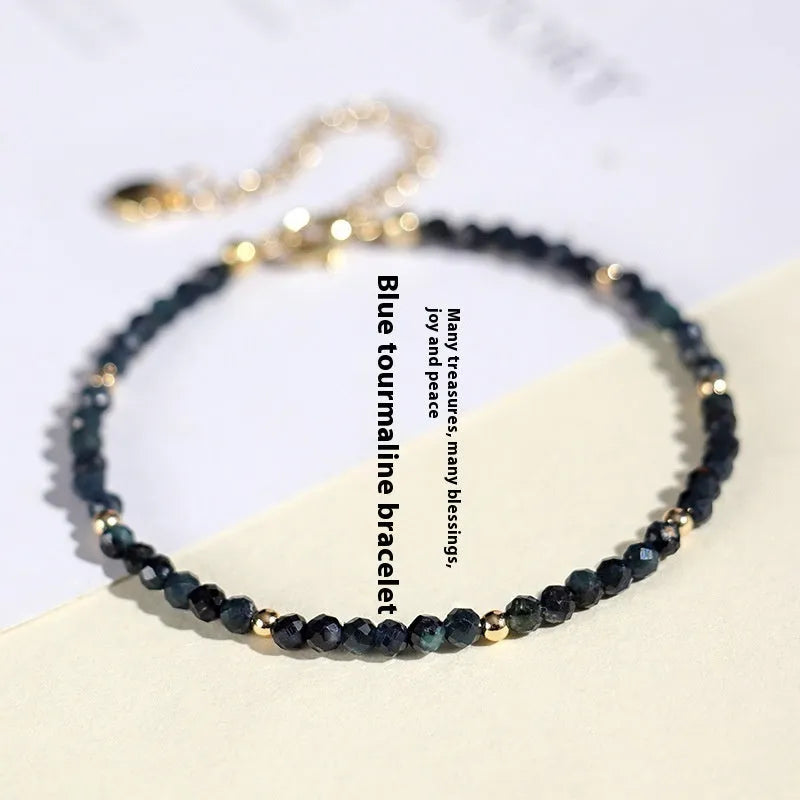 Blue tourmaline bracelet with 3mm beads and spacer beads on a wrist.
