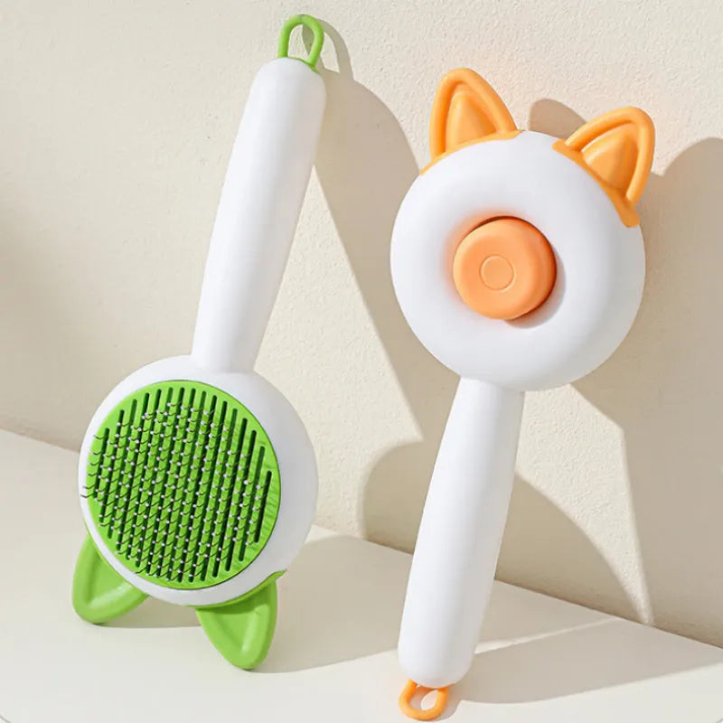 A greenish white and orange cat grooming comb with stainless steel teeth and a self-cleaning button.