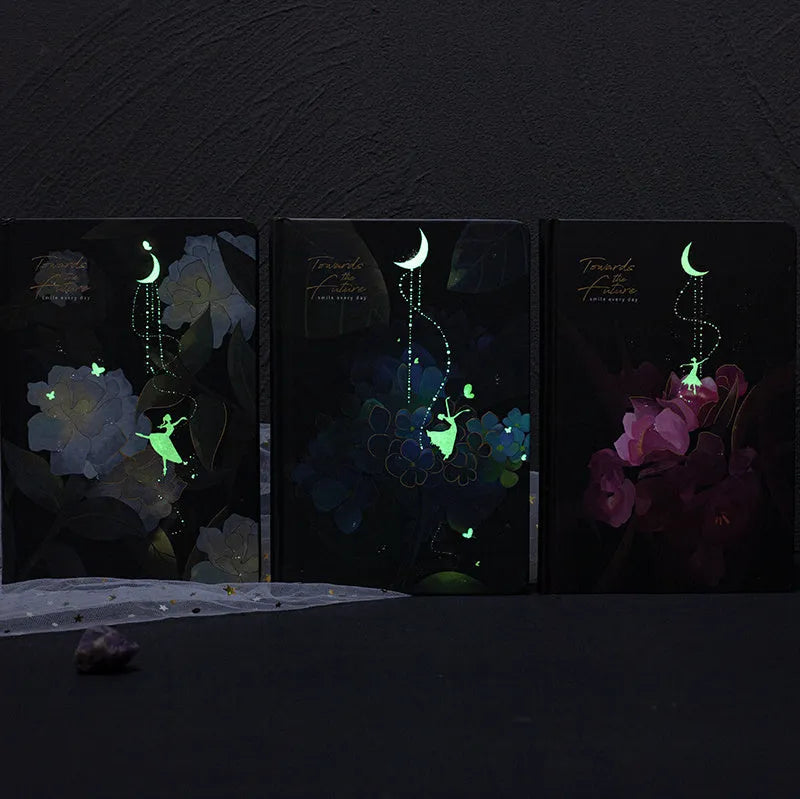 A5 notebook with luminous holographic cover lying flat, showing colourful illustrated interior pages.