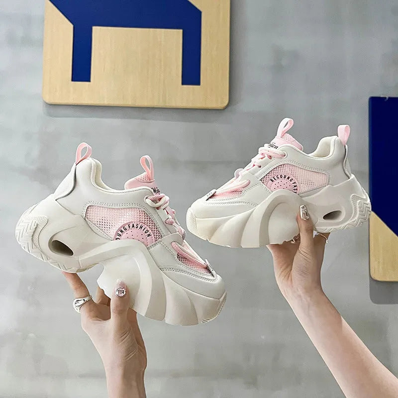 Women's pink casual sneakers with a cross strap, thick sole, and mesh lining on a white background.