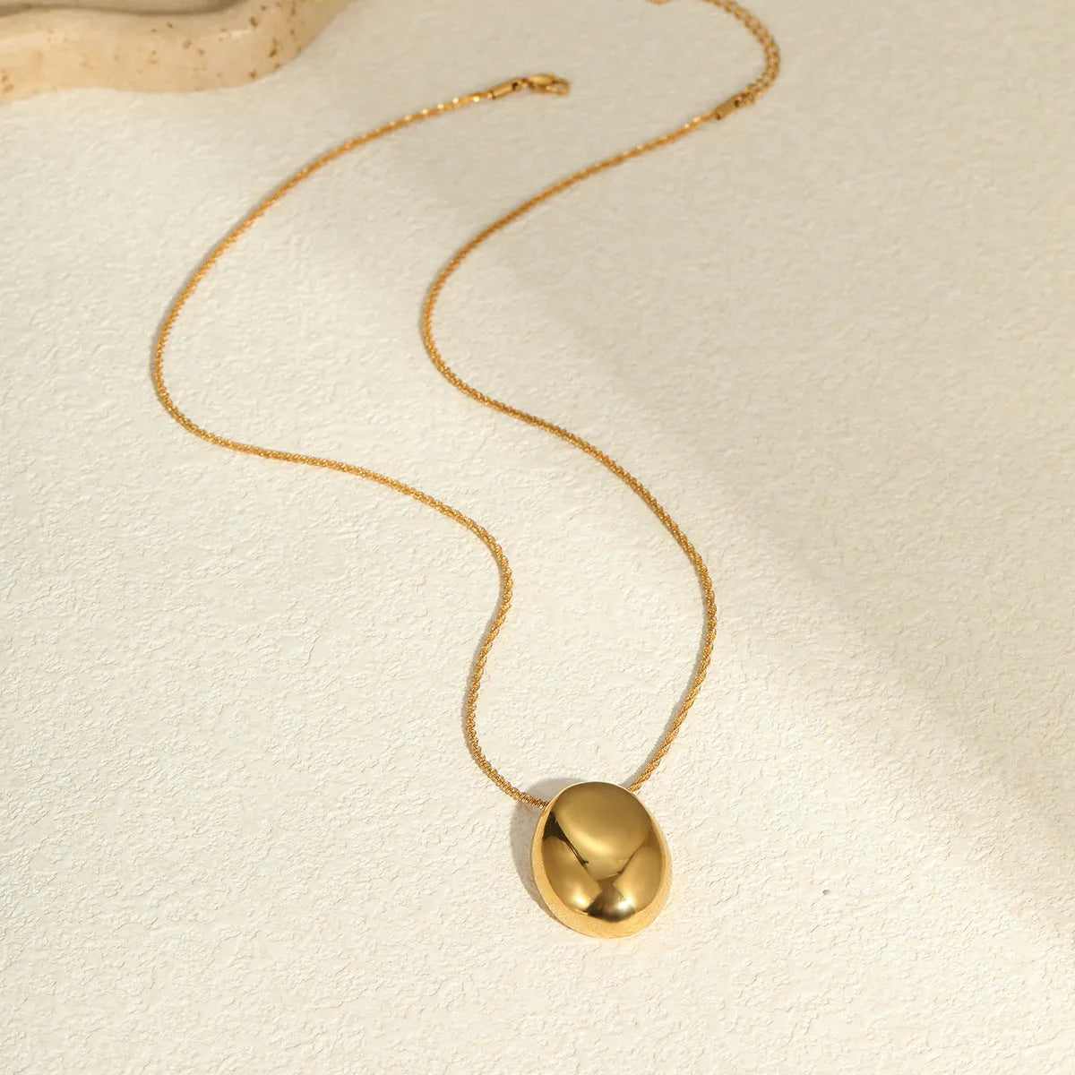 Gold geometric pendant necklace with adjustable chain on stainless steel background
