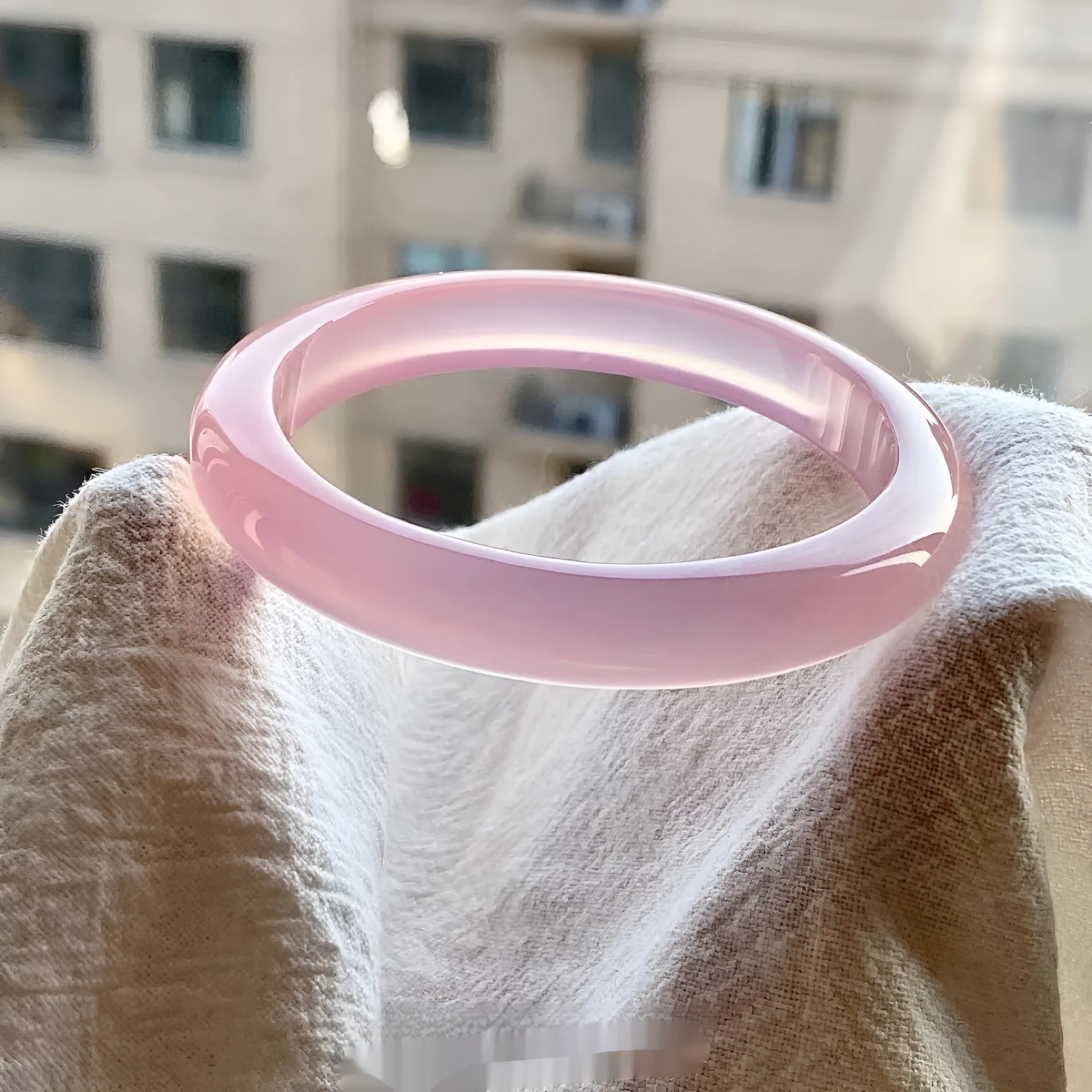 Natural agate wide tyre bracelet in pink on a wrist, showing bead detail and size.