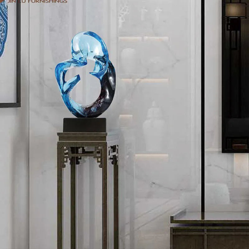Clear transparent resin sculpture ornament in modern style on a shelf, shown in blue and orange red colour options.