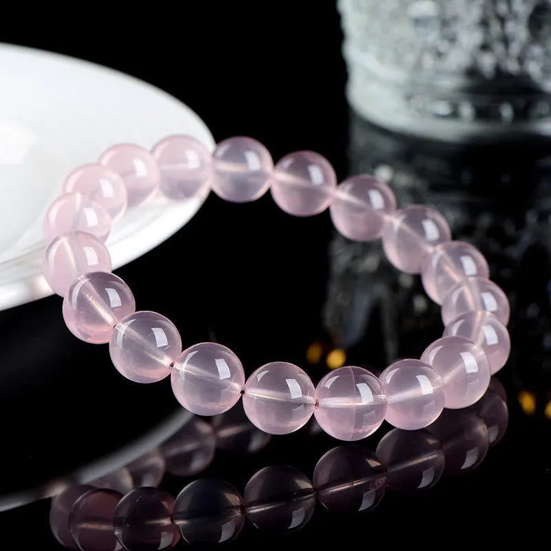 A pink crystal bead bracelet with polished round stones on a single strand.
