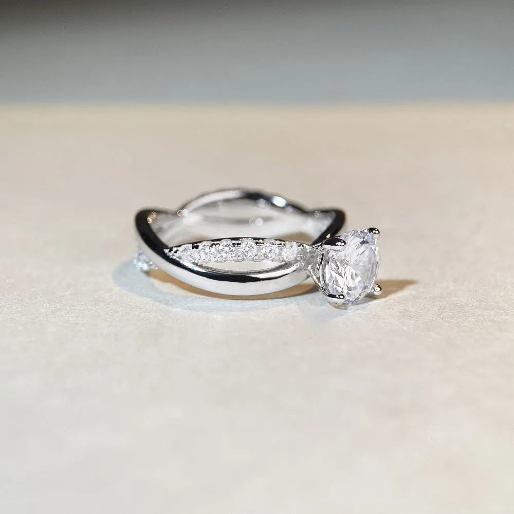 Geometric cross design moissanite ring with twisted sterling silver band and four-claw setting.
