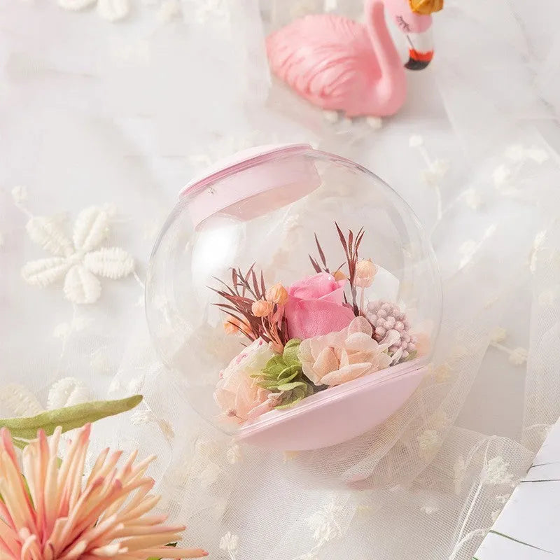 Pink preserved rose ornament with LED lights on a base with audio Bluetooth connectivity.