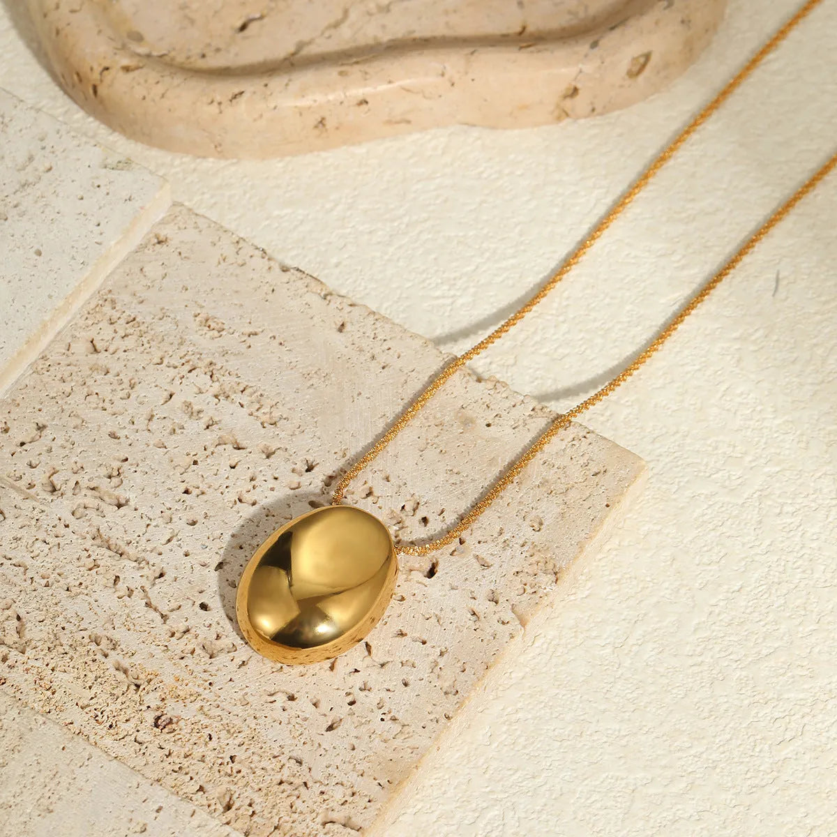Gold geometric pendant necklace with adjustable chain on stainless steel background