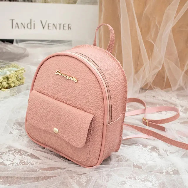 Small black PU leather women's shoulder backpack worn as a backpack, showing zipper closure and compact size.