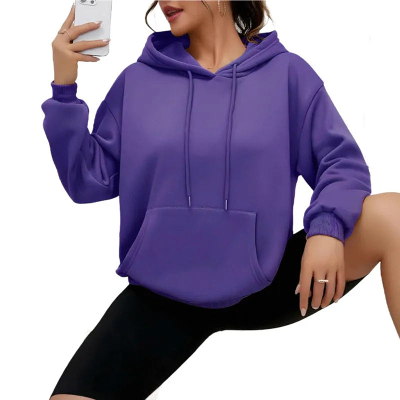 Woman wearing a loose grey sweatshirt with a front pocket and drawstring hem.