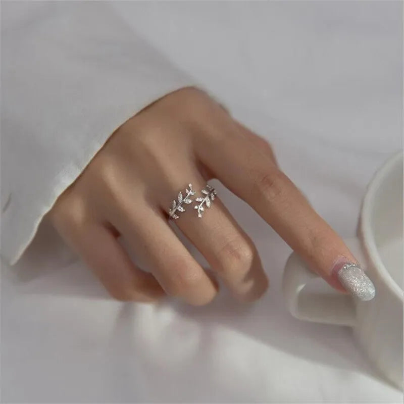 Close-up of a women's leaf-shaped branch fashion ring in a silver or gold electroplated finish on a copper base.