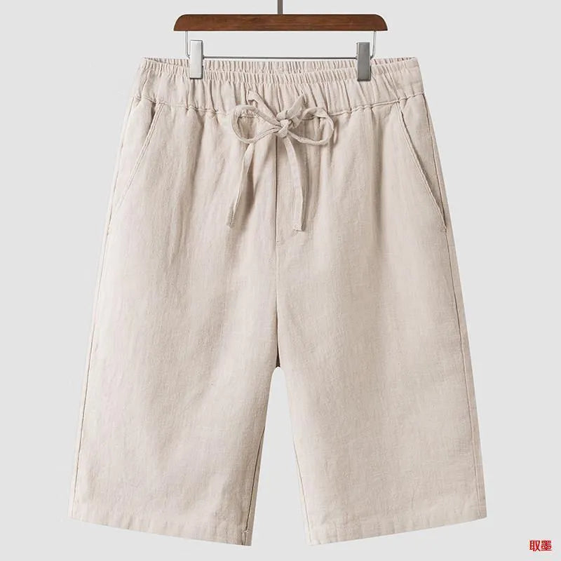 Men's beige linen shorts with a loose cropped fit and mid waistband.
