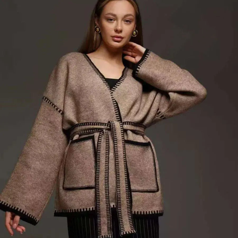 Loose mid-length knitted cardigan sweater coat with a lace-up front, shown in a neutral colour.