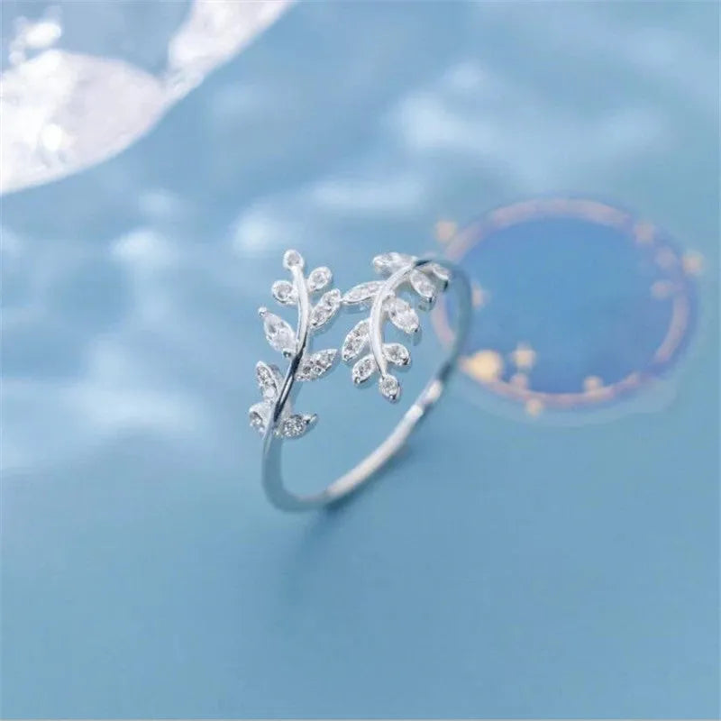 Close-up of a women's leaf-shaped branch fashion ring in a silver or gold electroplated finish on a copper base.